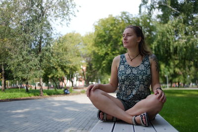 Full length of young woman sitting on bench at park