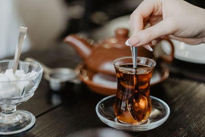 Midsection of person pouring coffee in cup on table