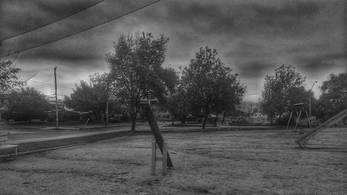 Trees on landscape against cloudy sky