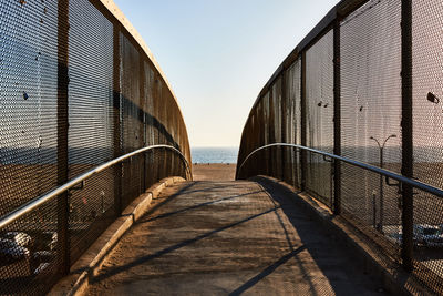 Footbridge over sea against sky