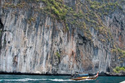 Man standing on boat in sea against mountain