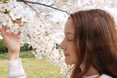 Portrait of young woman with cherry blossoms in spring