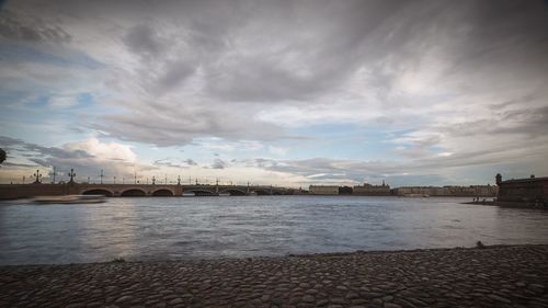 Bridge over river against cloudy sky