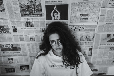 Portrait of smiling young woman standing against wall