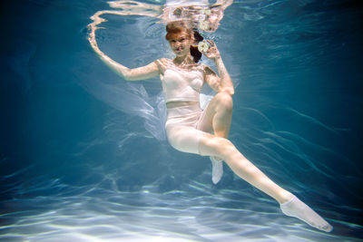 Portrait of young woman holding apple underwater