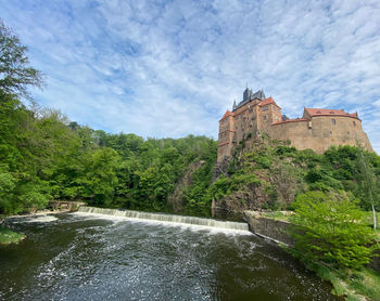 Building by river against cloudy sky