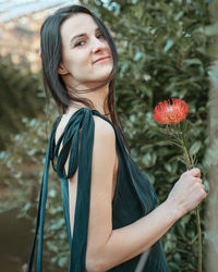 Portrait of young woman standing against tree