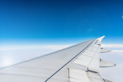 Airplane flying over clouds against blue sky