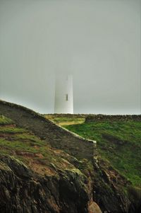 Lighthouse on field against sky