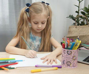 Girl writing in book on table