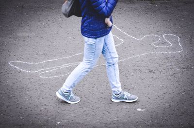 Low section of person walking by drawing on road