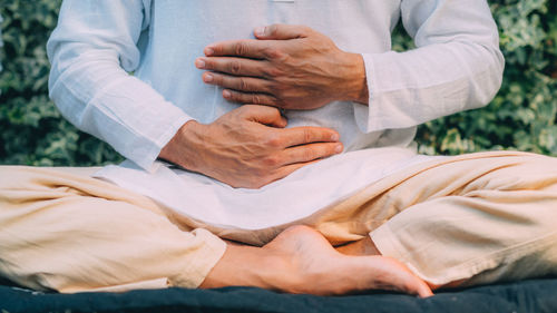 Male therapist performing reiki therapy self treatment holding hands over his stomach. 