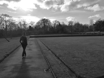 Rear view of woman walking on footpath against sky