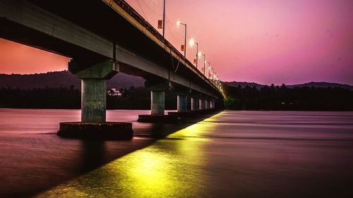 Bridge over river against sky at night