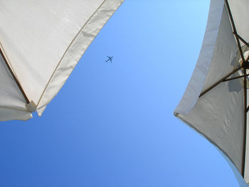 Low angle view of airplane flying against clear blue sky