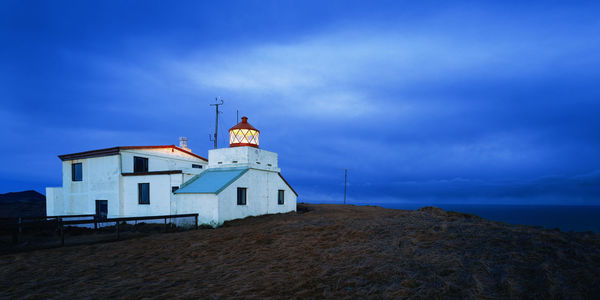 Lighthouse amidst buildings against sky