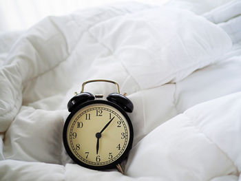 Close-up of alarm clock on duvet