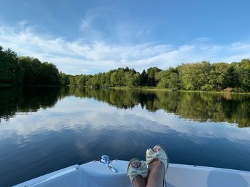 Low section of person by lake against sky