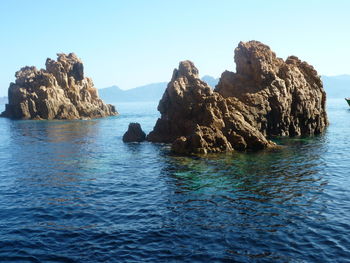 Rock formation in sea against clear blue sky