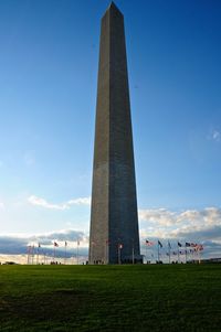 American flags at washington monument on field against blue sky