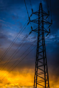 Low angle view of silhouette electricity pylon against sky at sunset