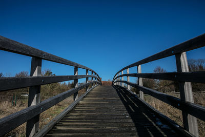 Footbridge against clear blue sky