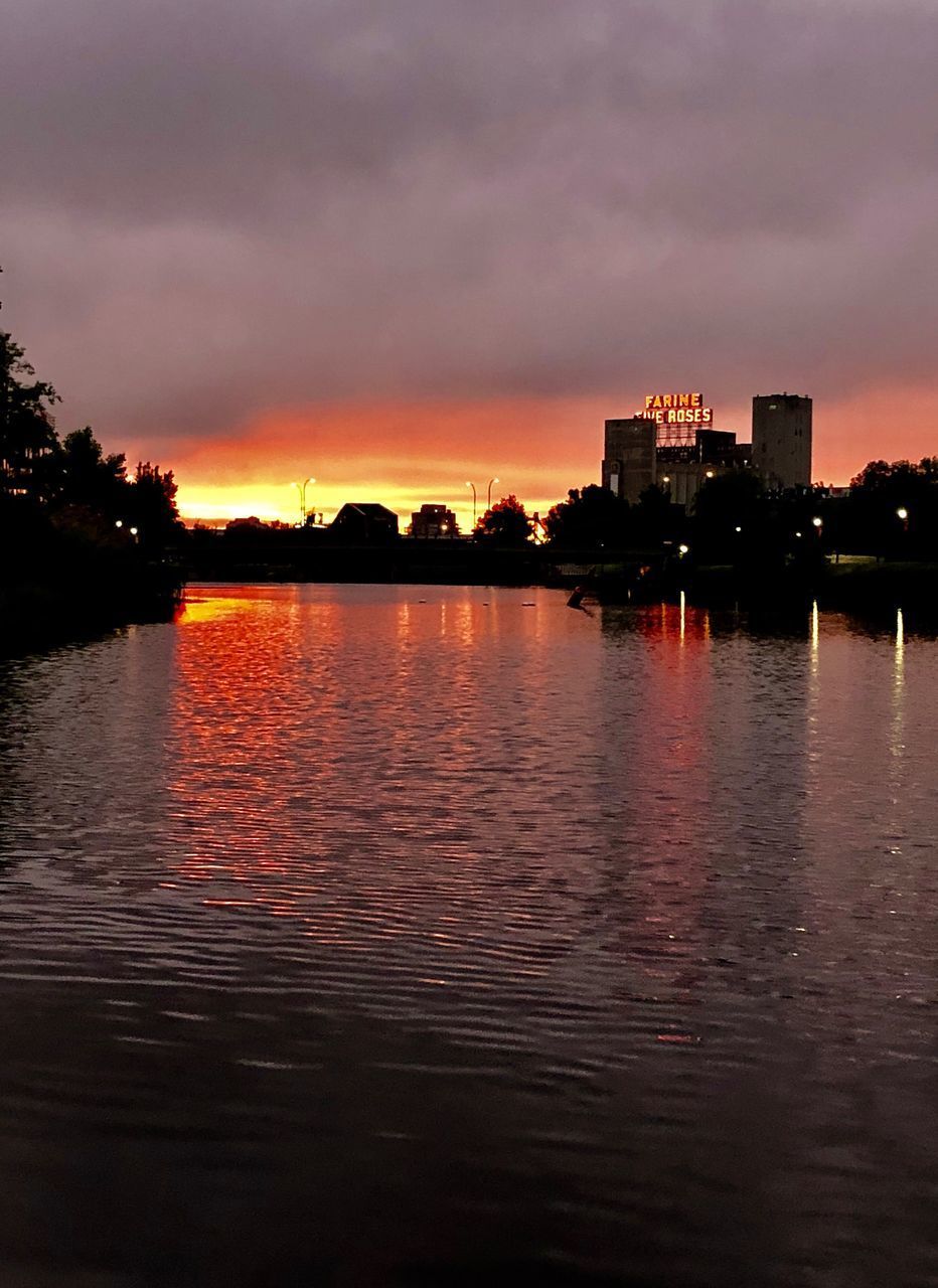 SILHOUETTE BUILDINGS BY LAKE AGAINST SKY DURING SUNSET IN CITY