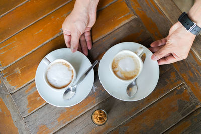 Midsection of woman holding coffee cup on table