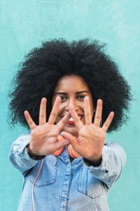 Portrait of smiling young man gesturing against wall