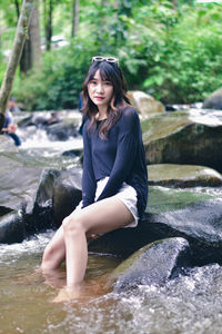 Portrait of young woman sitting in river