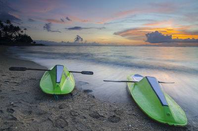 Boats moored on beach against sky during sunset