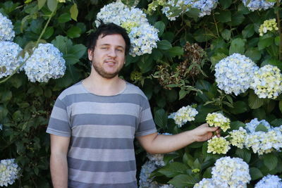 Portrait of smiling young woman against hydrangea flowers