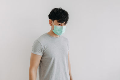 Portrait of young man standing against white background