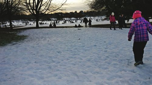 People on snow covered trees against sky