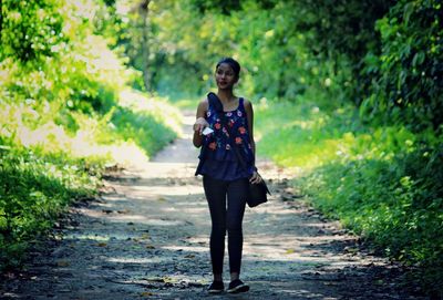 Woman walking on footpath against trees