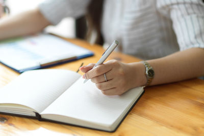 Midsection of woman reading book on table