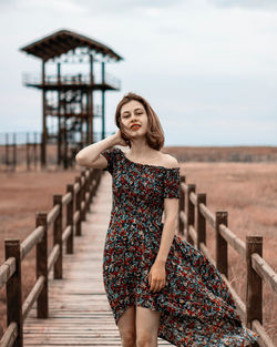 Portrait of beautiful young woman standing against sky