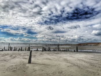 Scenic view of beach against cloudy sky