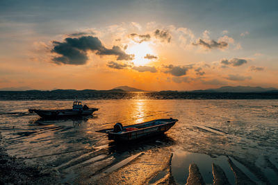 Boat moored on sea against sky during sunset