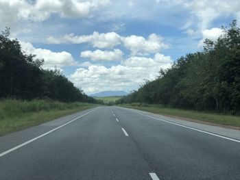 Empty road amidst trees against sky