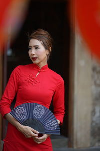 Beautiful woman holding hand fan while standing outdoors