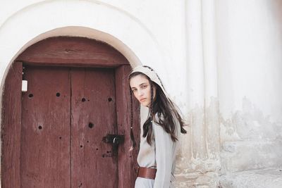 Portrait of beautiful woman standing against wall in winter