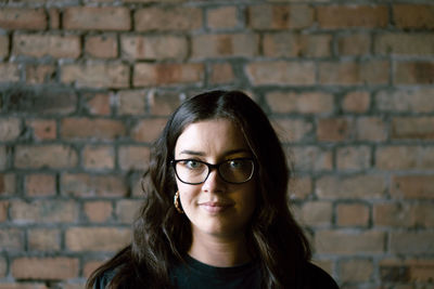 Portrait of smiling woman against brick wall