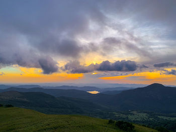 Scenic view of landscape against dramatic sky during sunset