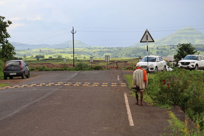 Rear view of man walking on road against sky