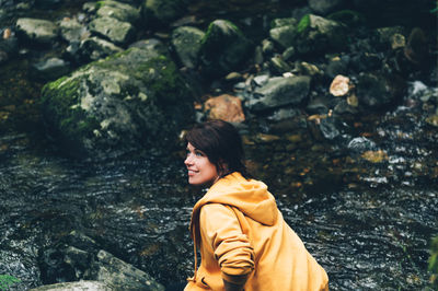 Young woman looking away while standing on rock