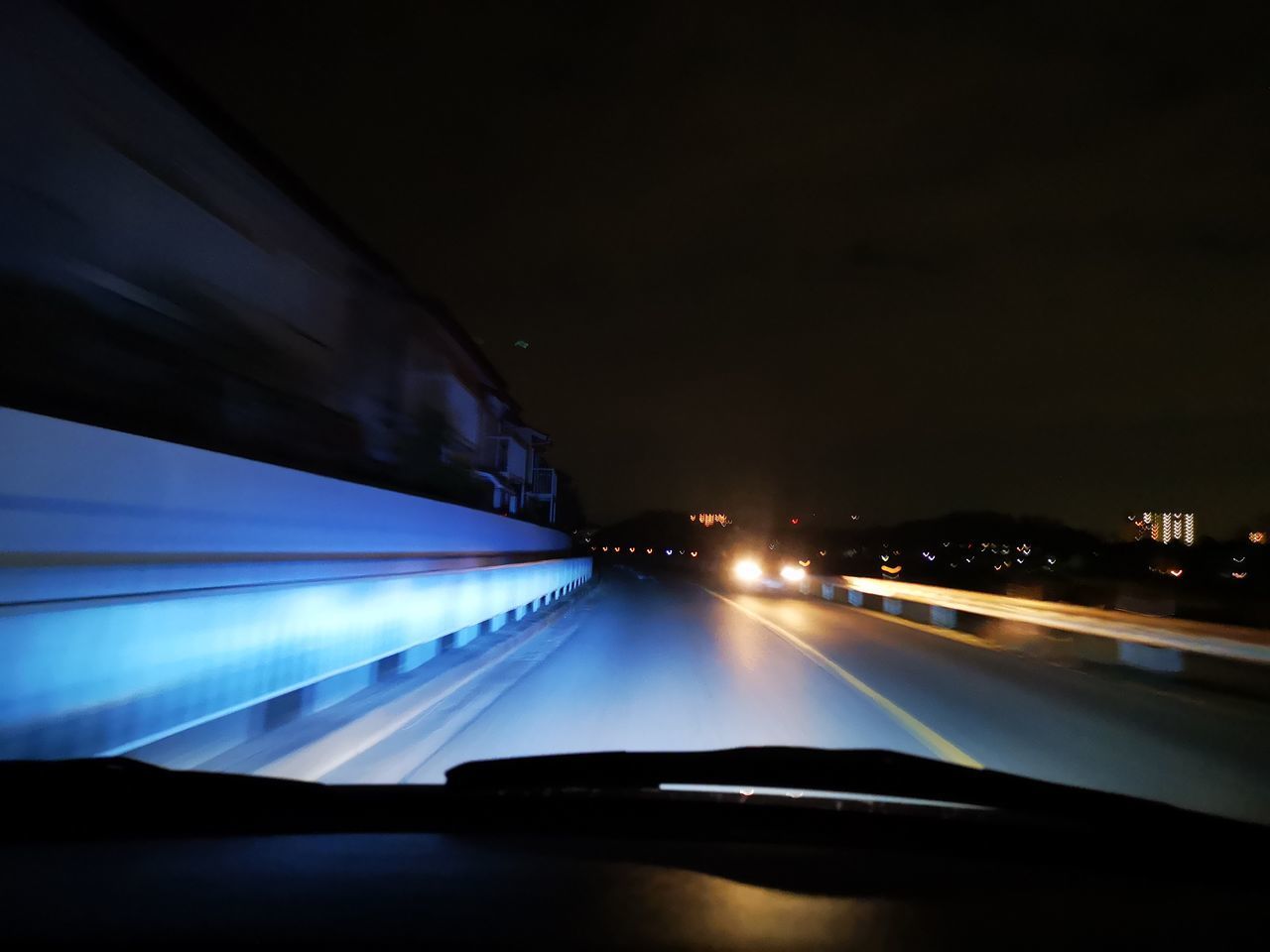 ILLUMINATED CAR ON ROAD SEEN FROM WINDSHIELD