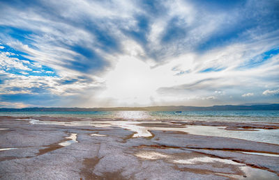 View of calm beach against cloudy sky