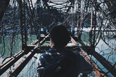Rear view of man on railing against sky