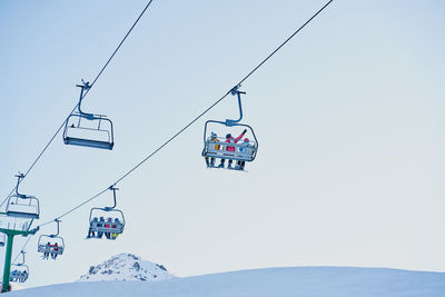 Skiers on a chairlift looking down with a blue background